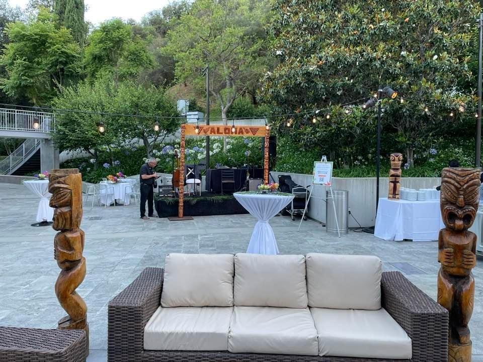 Outdoor tiki lounge with wicker sofa, tiki statues, and Aloha stage arch at a Las Vegas Strip corporate event